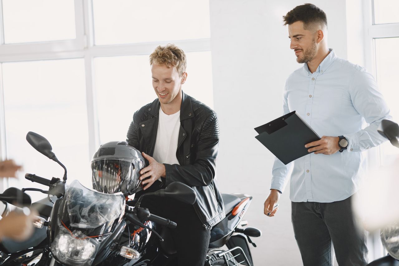 Un cliente y un asesor revisan una moto nueva dentro de una concesionaria